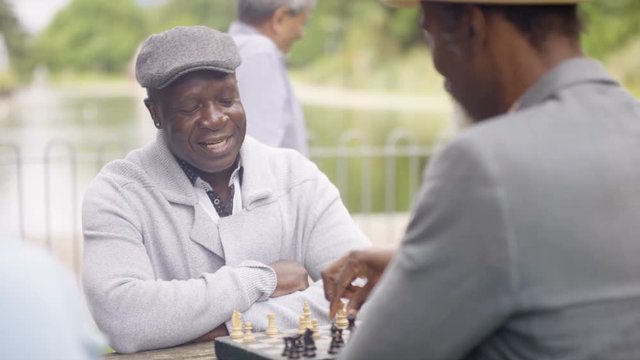  Portrait Smiling Senior Man Playing Chess In The Park With A Friend