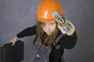 young woman in safety helmet and coverall holding hammer tool. Hammer in focus