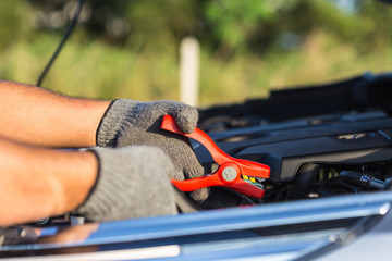Hand of car technician holding cable to connect to battery