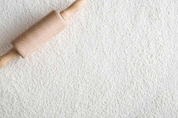 Rolling-pin on the white flour background in the kitchen.