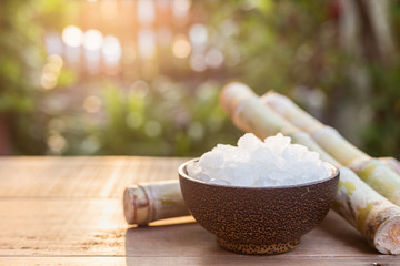 Rock sugar and sugar cane on wooden table with sunlight blur background