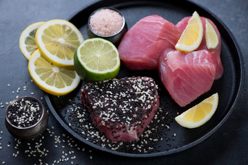 Fresh uncooked slices of tuna fillet with black and white sesame seeds, lemon and lime, studio shot