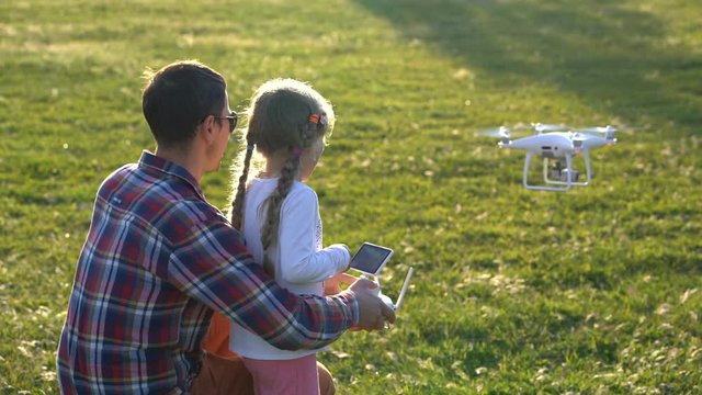 father shows his daughter how to control drone