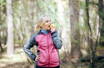 The girl athlete is eating an Apple in the forest © kamaz007