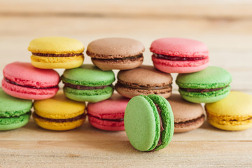 Fototapeta na wymiar Green, pink, yellow and brown french macarons on the wooden boards