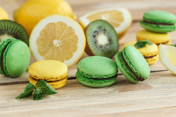 Green and yellow french macarons with kiwi, lemon and mint decorations