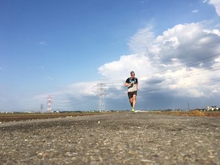 Man running on open country road with blue sky after storm