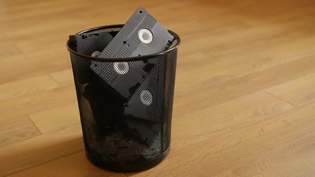 A bunch of VHS cassettes thrown in the trash over wooden background. UHD