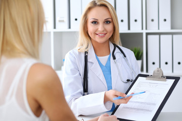 Doctor and  patient  discussing something while physician pointing into medical history form at clipboard. Medicine and health care concept