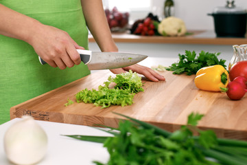 Close up of  woman's hands cooking in the kitchen. Housewife slicing ​​fresh salad. Vegetarian and healthily cooking concept