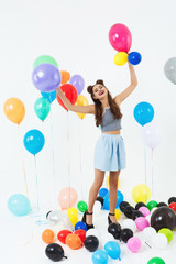 Fototapeta na wymiar Beautiful woman on high heels looks happy playing with balloons