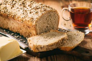Homemade bread loaf with sunflower seeds on wooden background.