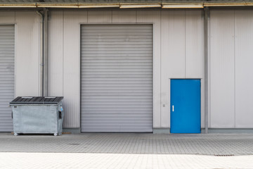 Silbernes Rolltor mit Container und blauer Tür