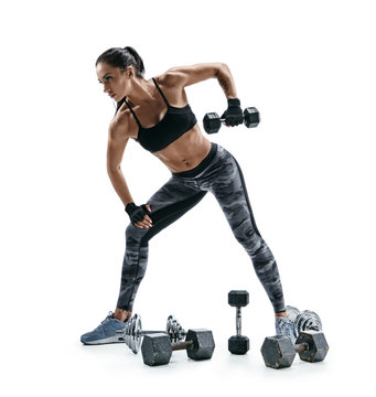 Athletic woman doing exercise for arms. Photo of muscular fitness model working out with dumbbells on white background. Strength and motivation