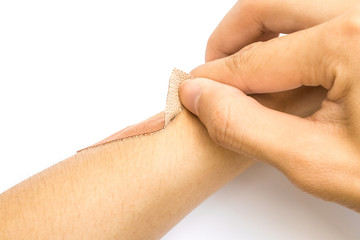 hand removing medical plaster band on arm on white background