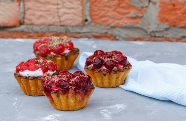 Homemade cake of sweet berry baskets with cherries and raspberries on the background of a peeling wall.