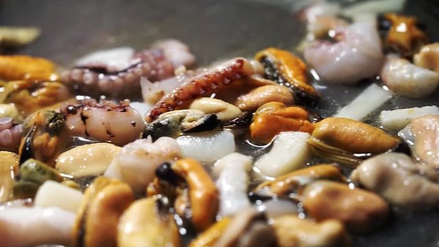 Seafood mussels, squid, octopus and prawn are cooking in a pot. Paella cooking, Dolly motion.