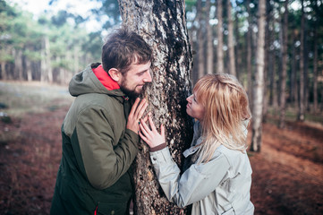A loving guy with a girl is walking through the woods in the rain.