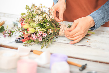 Obraz na płótnie Canvas Florist at work: the female hands of woman making fashion modern bouquet of different flowers