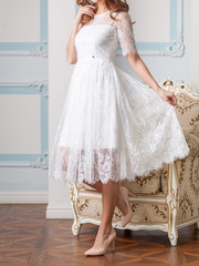 Obraz na płótnie Canvas Attractive blond woman in white lace dress with beautiful long hair posing against the expensive antique armchair