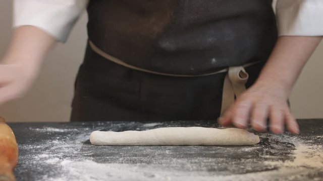 Two woman's hands making meat dumpling with wooden rolling pin.