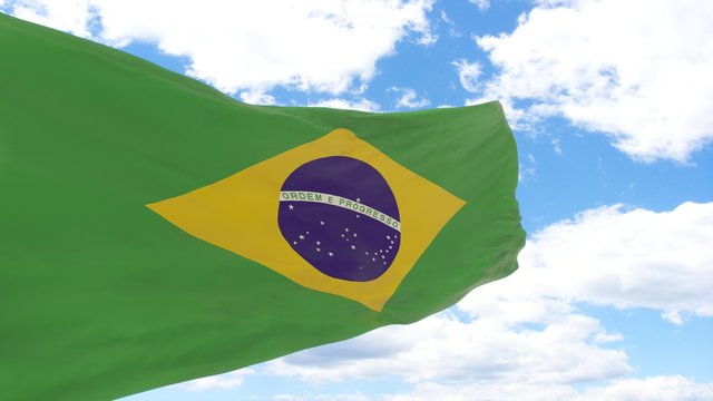 Waving flag of Brazil on a blue cloudy sky.