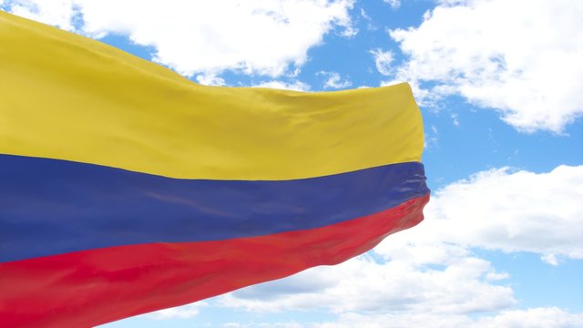 Waving flag of Colombia on a blue cloudy sky.