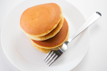 Pancakes on white disk and background with silver fork