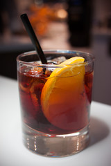 Cocktail on the white bar counter. Piece of citrus and ice