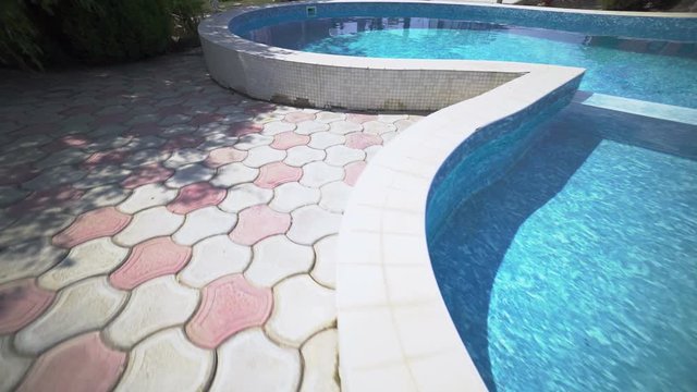 Camera moves along private swimming pool with paved deck at vacation home