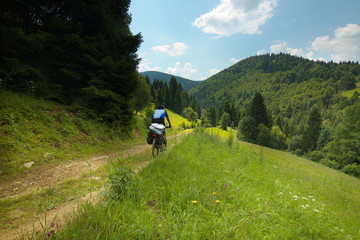 A tourist riding on bicycle with forest hills