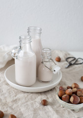 Vegan milk from nuts in glass jar. Hazelnut vegetarian drink on white rustic background