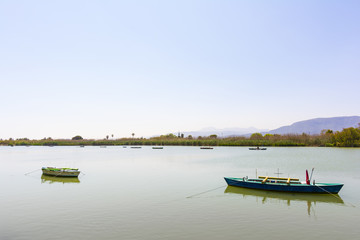 Calm lake with two fishing boats. Fresh water lagoon in Estany de cullera. Valencia, Spain