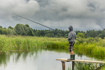 Teen boy fishing on wooden pier