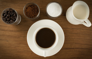 Coffee cup with ingredients on old wooden boards