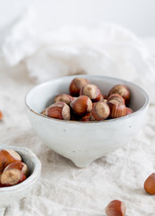 Hazelnuts in white rustic dish on white background