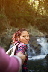  Happy young woman holding hand of her boyfriend in the river.