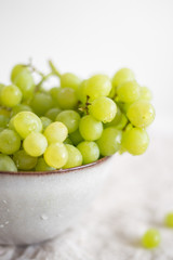 Green Grapes in old rustic bowl on white textile background