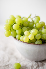 Green Grapes in old rustic bowl on white textile background