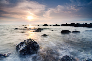 Panele Szklane Podświetlane  Wspaniały zachód słońca moment seascape, miękka fala uderzająca w skałę nad zachmurzonym niebem. nieskończoność ostrości i ujęcie z długim czasem naświetlania