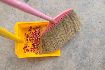 Broom sweeping floor into dustpan.