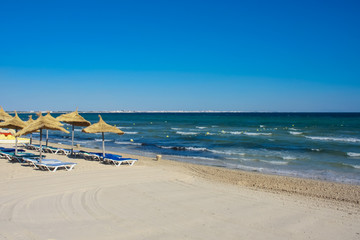 Fototapeta na wymiar sand beach with thatched umbrellas and parasols