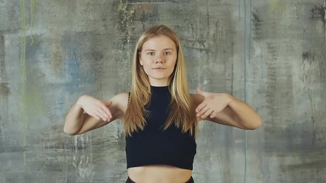 Beautiful blond hair girl dancing hiphop on the gray wall. Slow motion shooting. Actively works with hands.