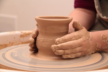 Fototapeta na wymiar Hands of a potter, creating an earthen jar on pottery wheel.