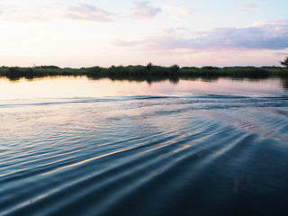 Sunset scene at the river bank with water ripple and reflection