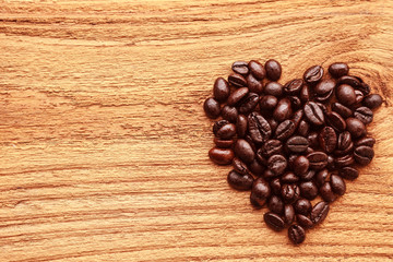 Heart from of coffee beans on vintage wooden background