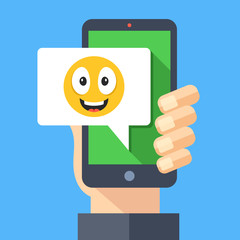 Hand holding smartphone with happy emoji message on screen. Happy emoticon icon. Social networking, instant messaging on mobile device, online chat concepts. Modern flat design vector illustration