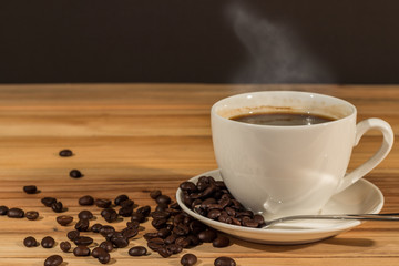 Coffee cup and coffee beans on wood table blurry background