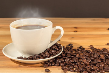 Coffee cup and coffee beans on wood table blurry background