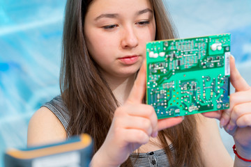 Student girl in electronics laboratory, experiment with microcontroller and robot cnc module
